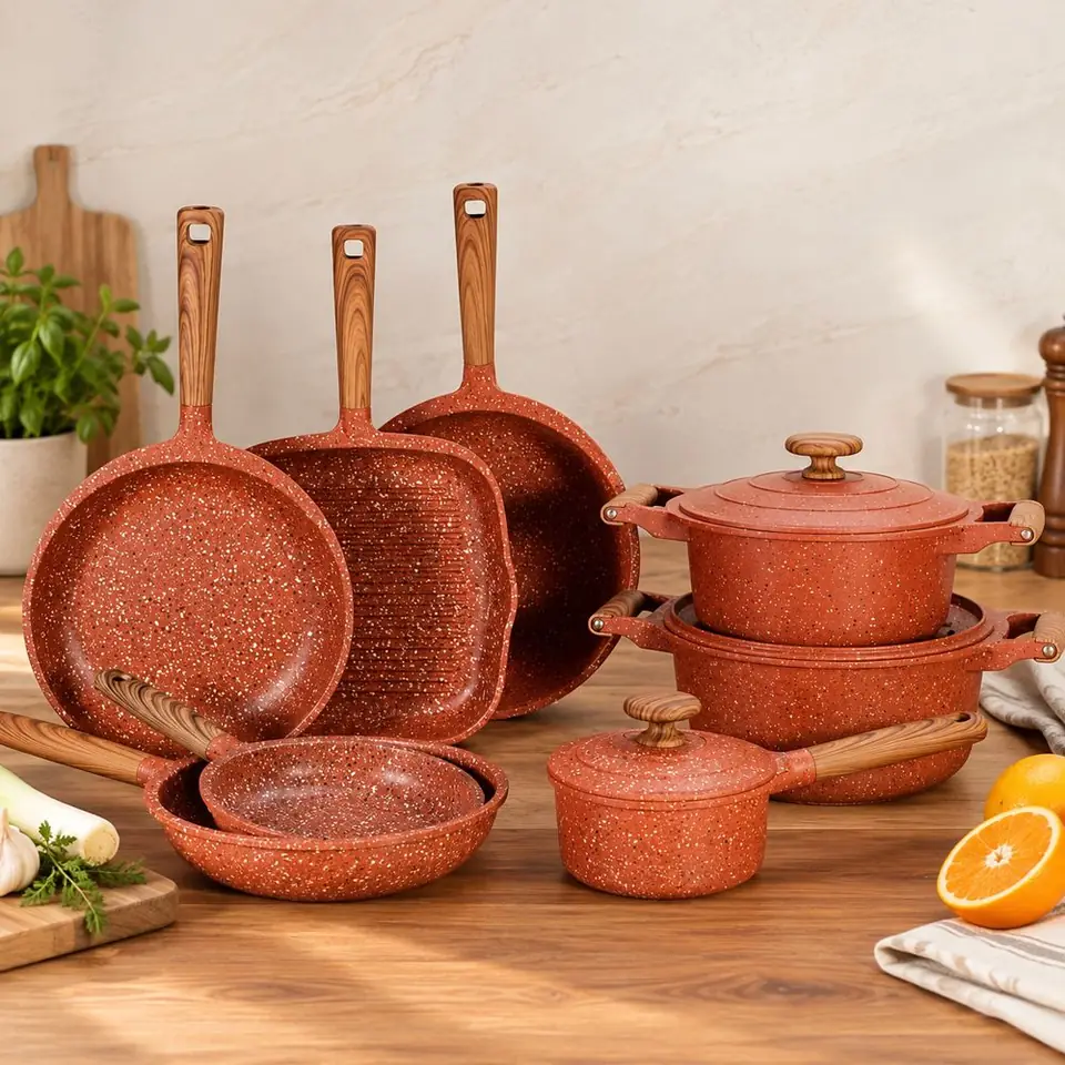 Colección de sartenes y ollas color terracota sobre una mesa de madera en una cocina luminosa