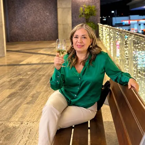 Myriam Lugo sentada en una banca con una copa en la mano