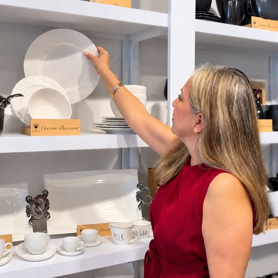 Myriam Lugo tomando un plato de una repisa llena de vajilla blanca